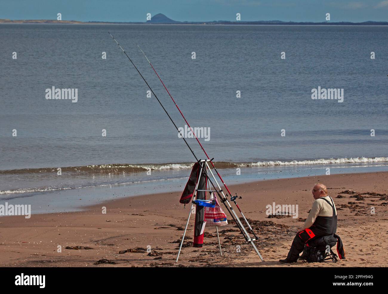 Portobello beach, Edinburgh, Scotland, UK. 17 March 2023. Sunny and 13 degrees centigrade for this lone sea fisherman with his lines out in the Firth of Forth. Credit: Archwhite/alamy live news. Stock Photo