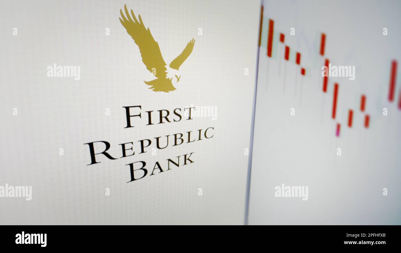 March 17th 2023 New York. The First Republic Bank logo through a glass, with a blur alert sign reflection, and a blur stocks chart on a screen. Stock Photo