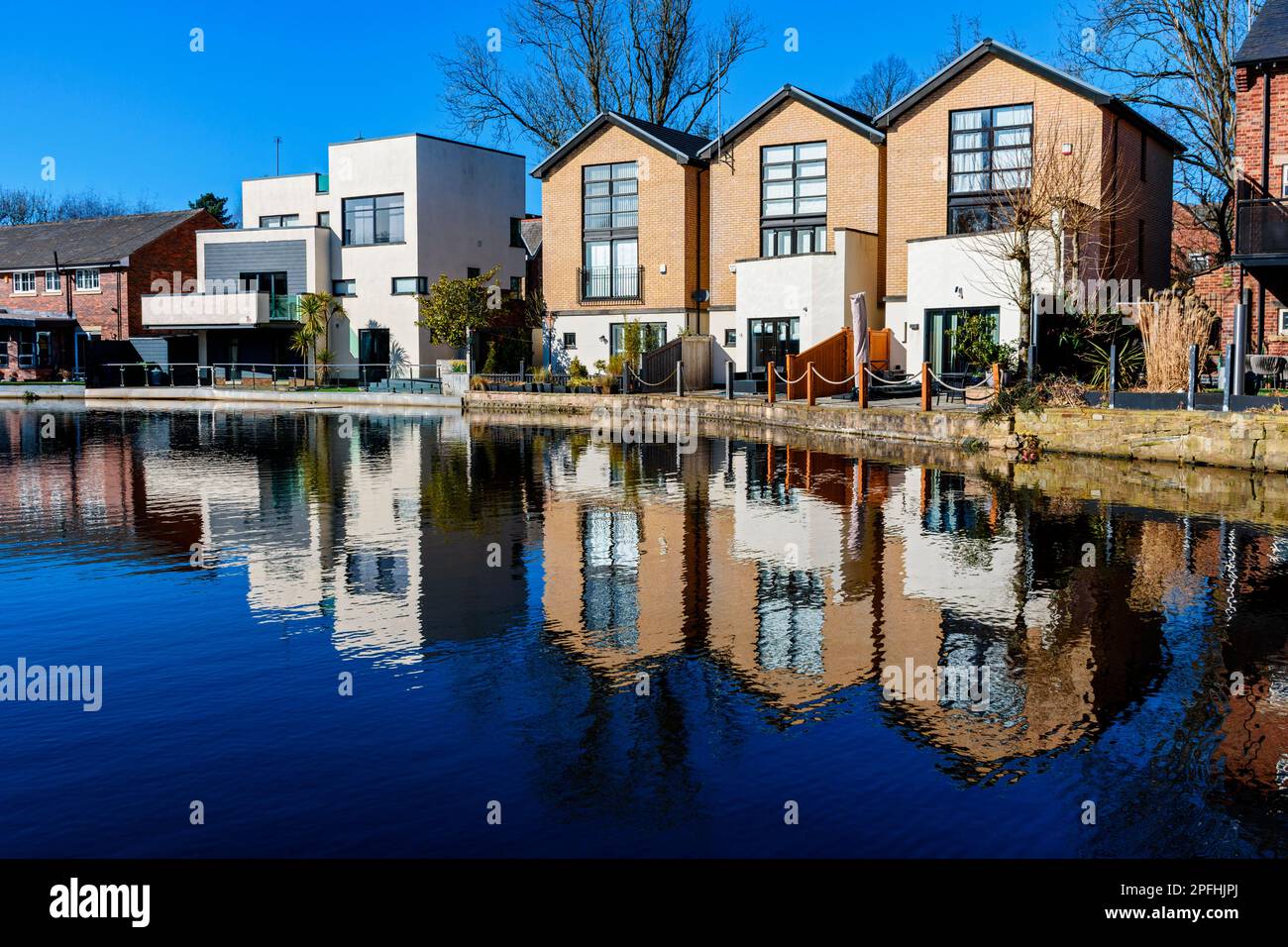 Modern houses reflected in the Ashton Canal, Audenshaw, Tameside, Manchester, England, UK.  The three on the right are called 'The Boatyard'. Stock Photo