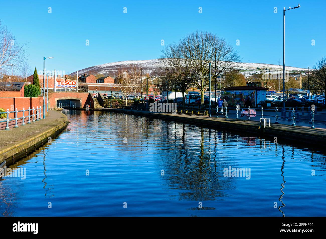 The Huddersfield Canal at Armentieres Square, Stalybridge, Tameside, Manchester, England, UK.  Snow covered Wild Bank Hill behind. Stock Photo