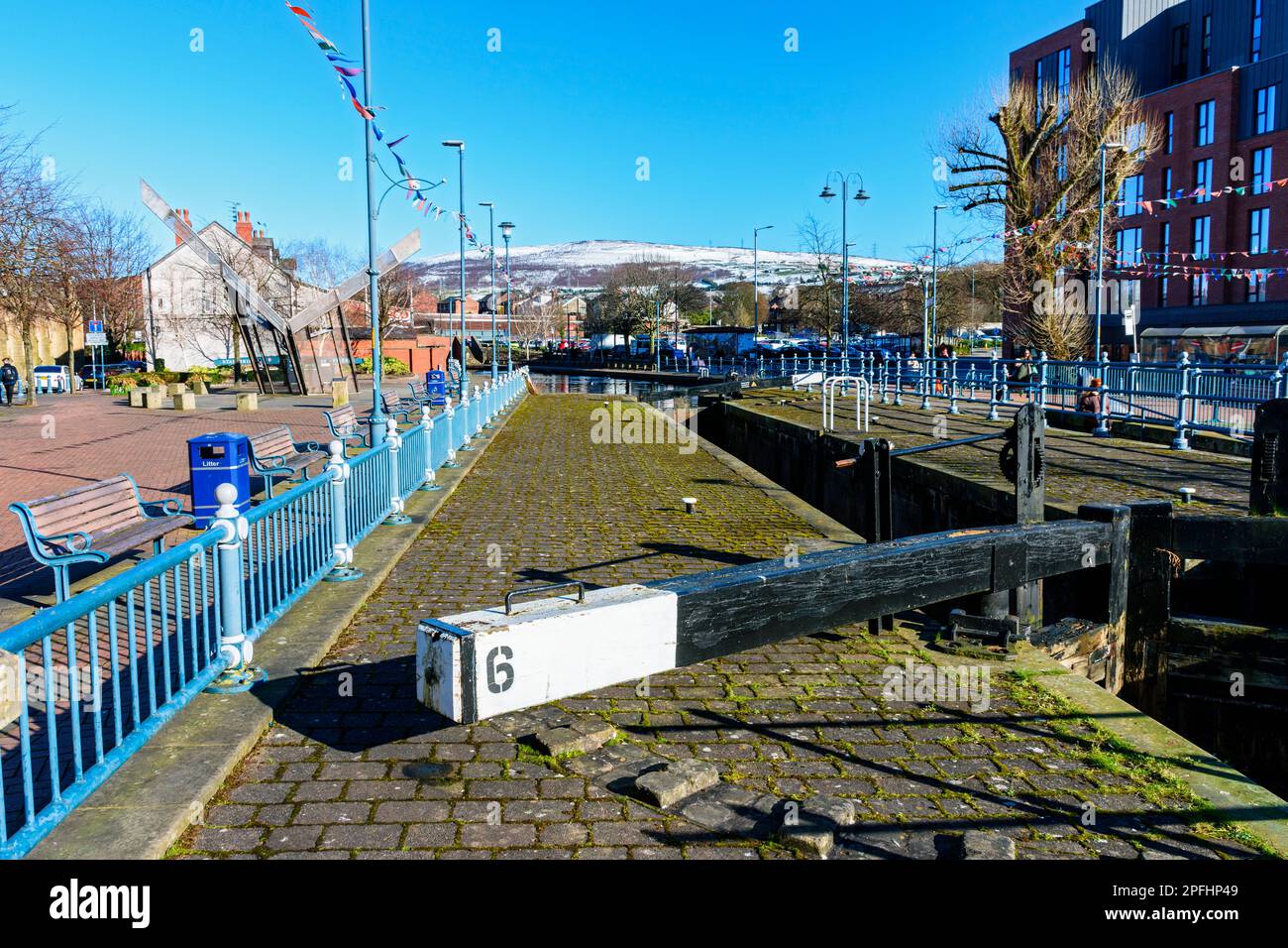 Lock 6 on the Huddersfield Canal at Armentieres Square, Stalybridge, Tameside, Manchester, England, UK.  Snow covered Wild Bank Hill in the distance. Stock Photo
