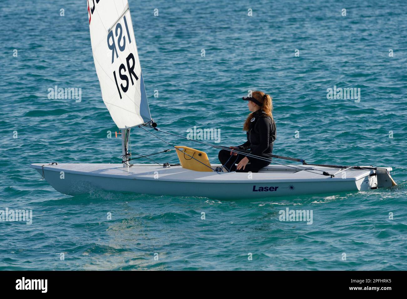 Photo of a teenage girl sailing a laser class sailboat with sea all