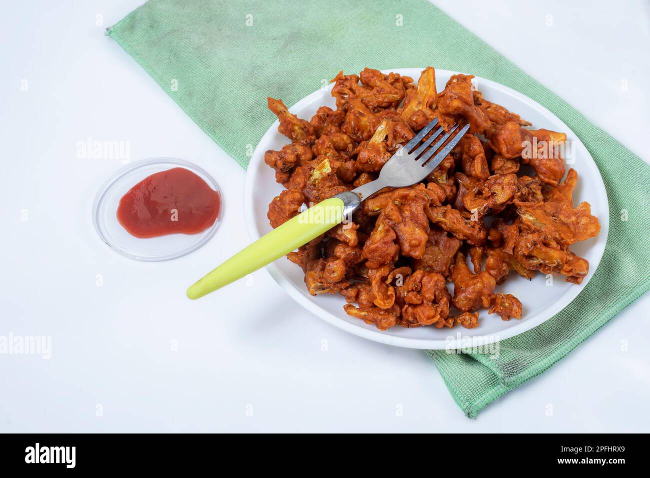 Fried Gobi Manchurian Dry with tomato sauce on white plate with green