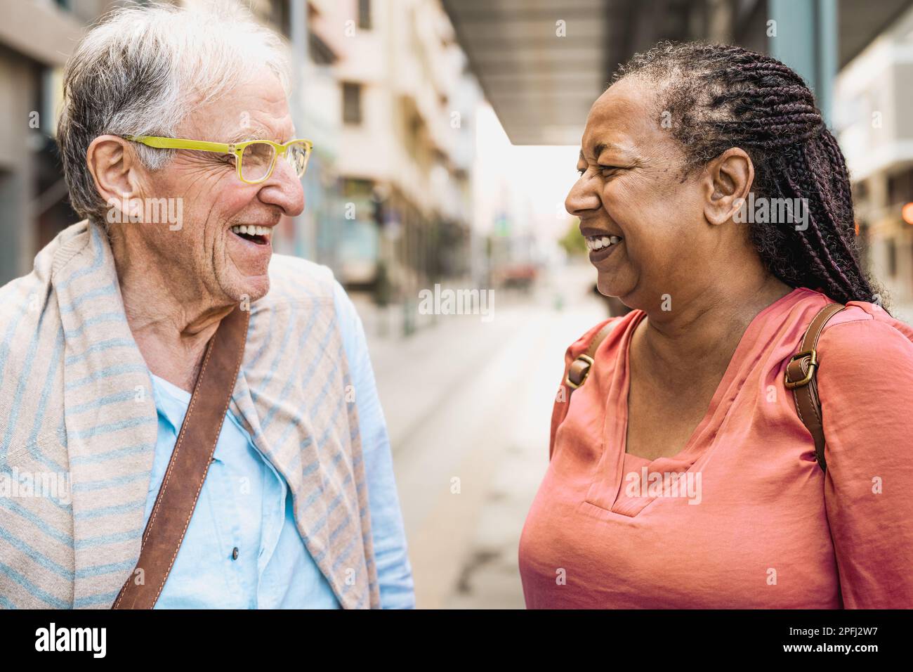 Happy multiracial senior friends talking while waiting at the bus station Stock Photo