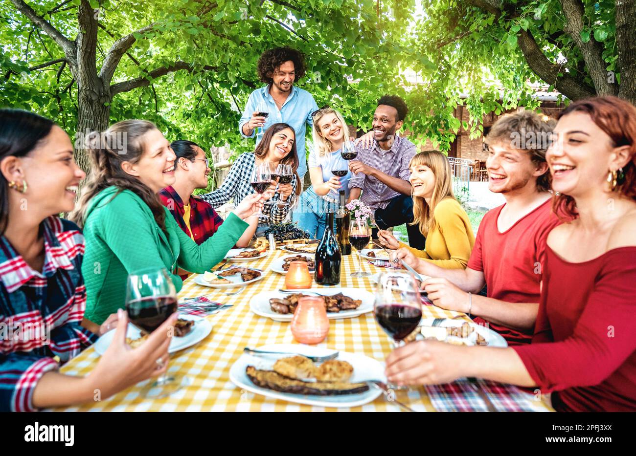 Happy people having fun toasting wine out side - Diverse friends sharing harvest together at farm house vineyard countryside - Food life style concept Stock Photo