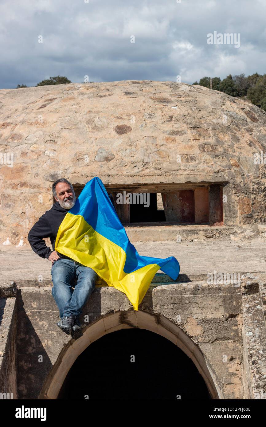 Adult man holding a Ukrainian flag in a defensive military structure, a bunker. Stock Photo