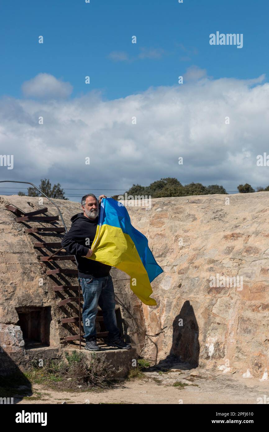 Adult man holding a Ukrainian flag in a defensive military structure, a bunker. Stock Photo