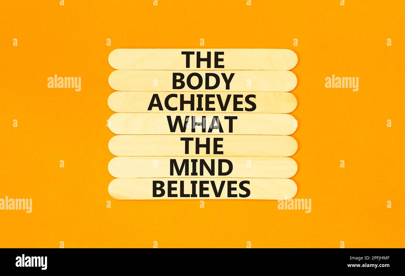 Mind and body symbol. Concept words The body achieves what the mind believes on wooden stick. Beautiful orange table orange background. Copy space. Mo Stock Photo