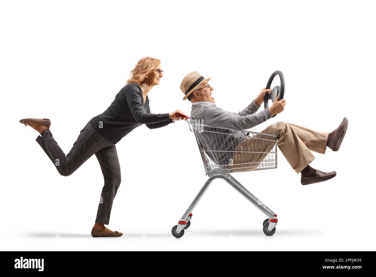 Woman pushing an elderly man inside a shopping cart holding a steering wheel isolated on white