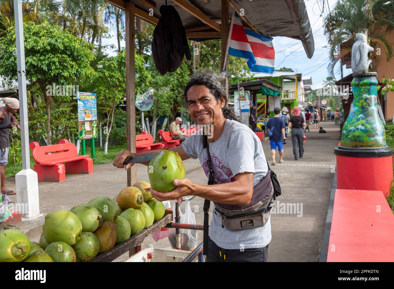Tortuguero, Costa Rica - A street vendor cuts open a green coconut for a tourist in this small village on the Caribbean coast. The refreshing coconut Stock Photo