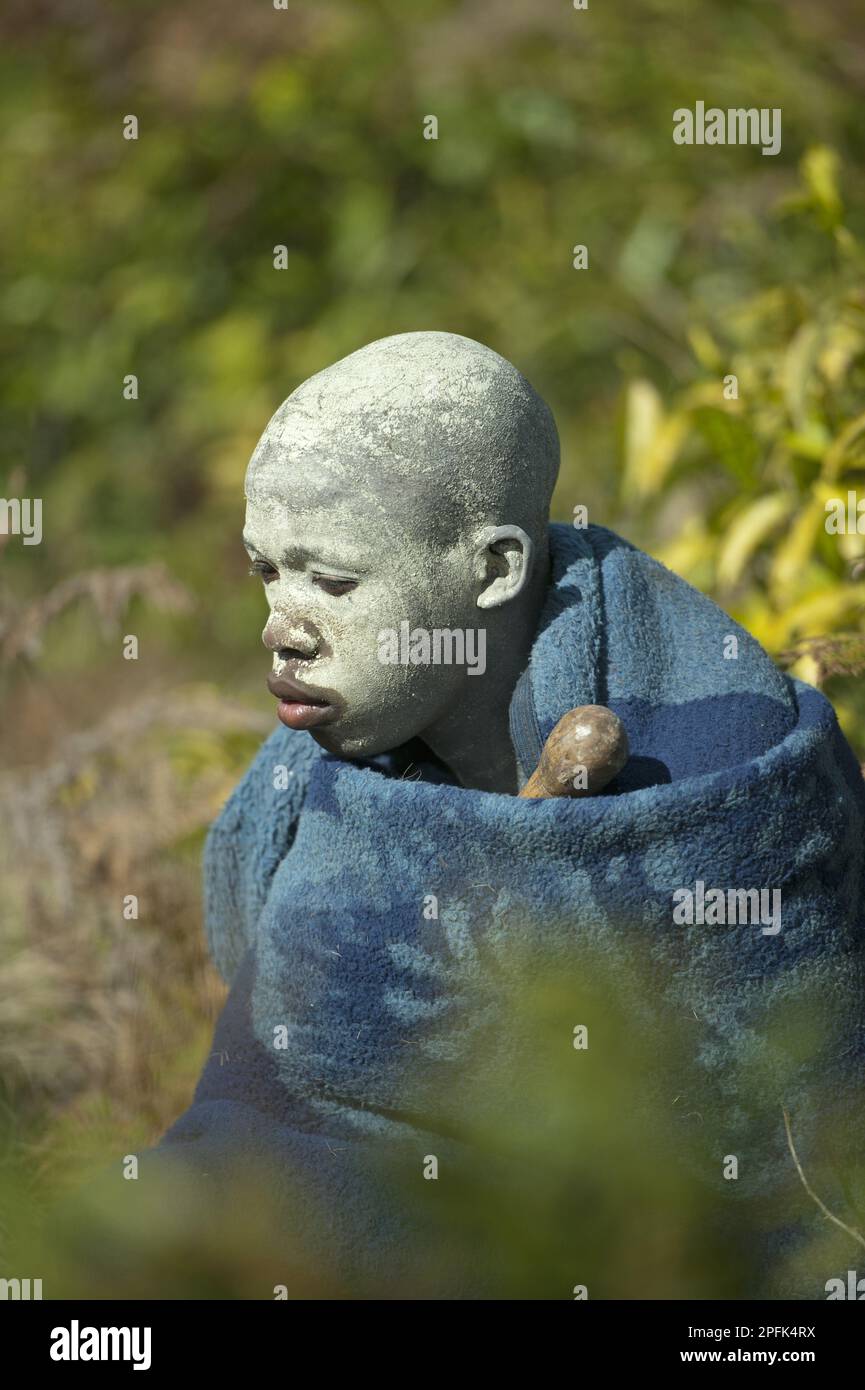AmaPondo (Xhosa) boy wrapped in rugs with white clay (I-Futa) on face, after being circumcised (uku-Lukwa) and having finished initiation, seclusion Stock Photo