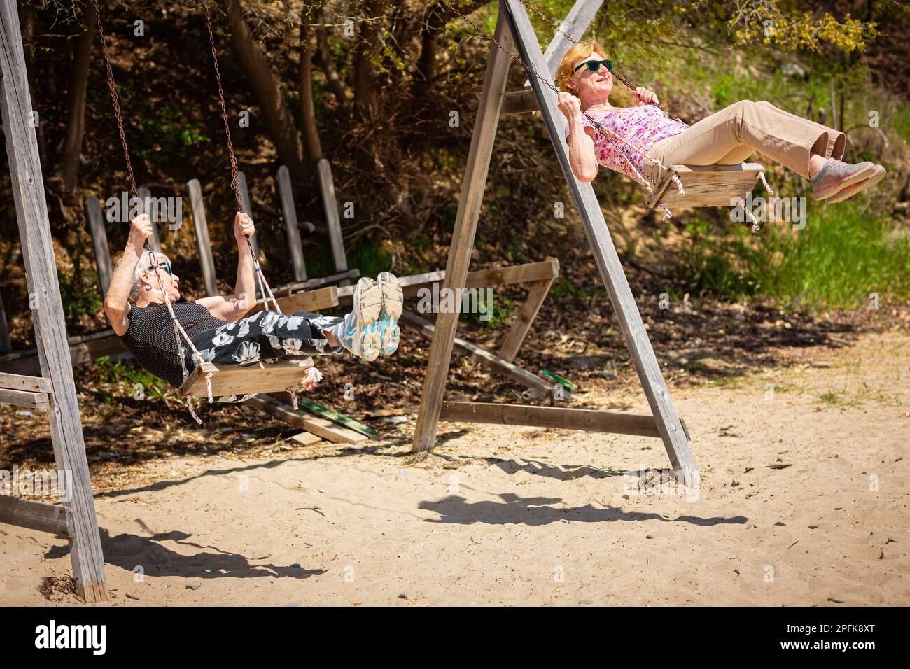 Two elderly women joyfully swinging on a swing Stock Photo