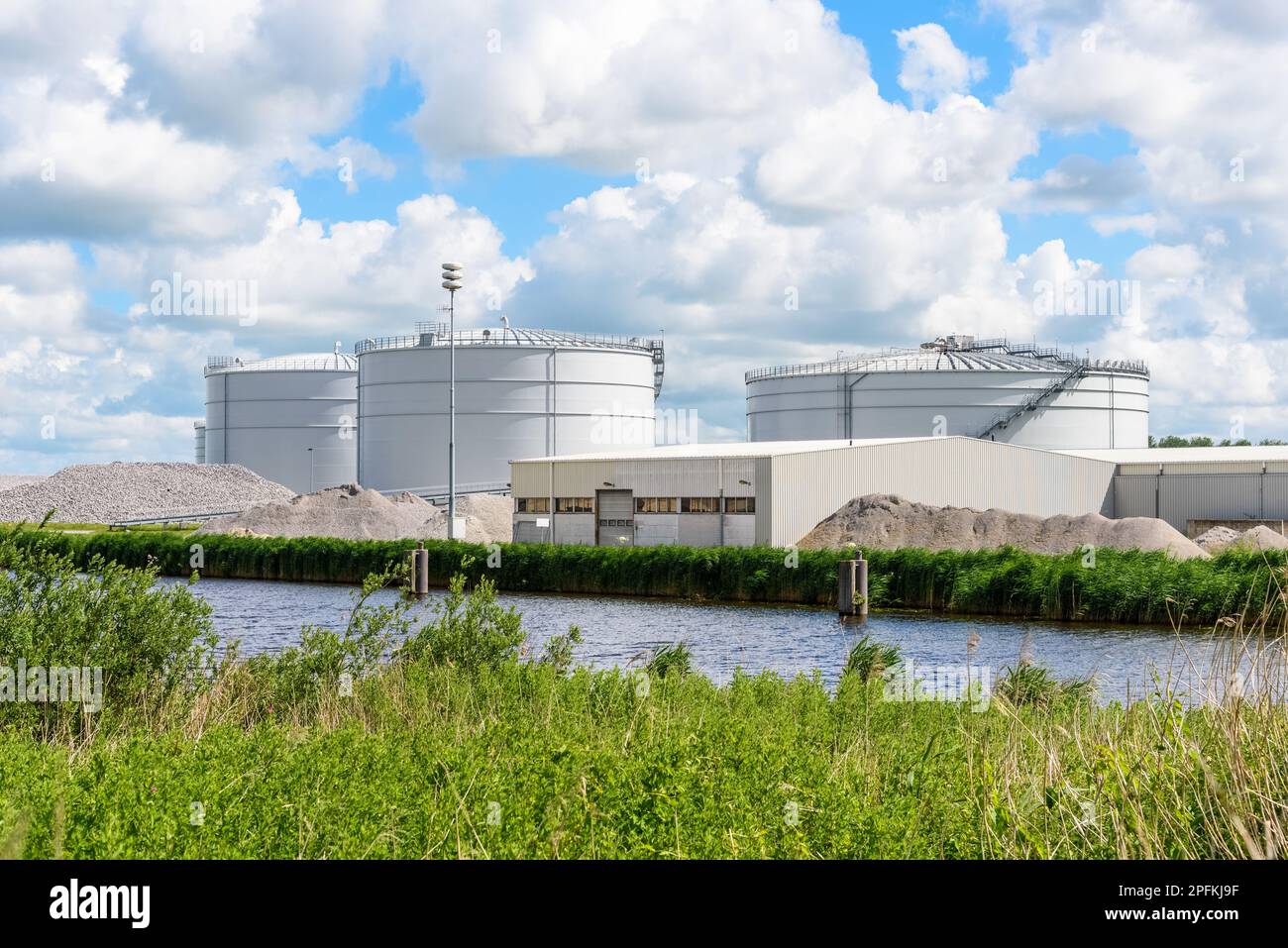 Biogas plant with large biomass digesters along a canal on a sunny ...