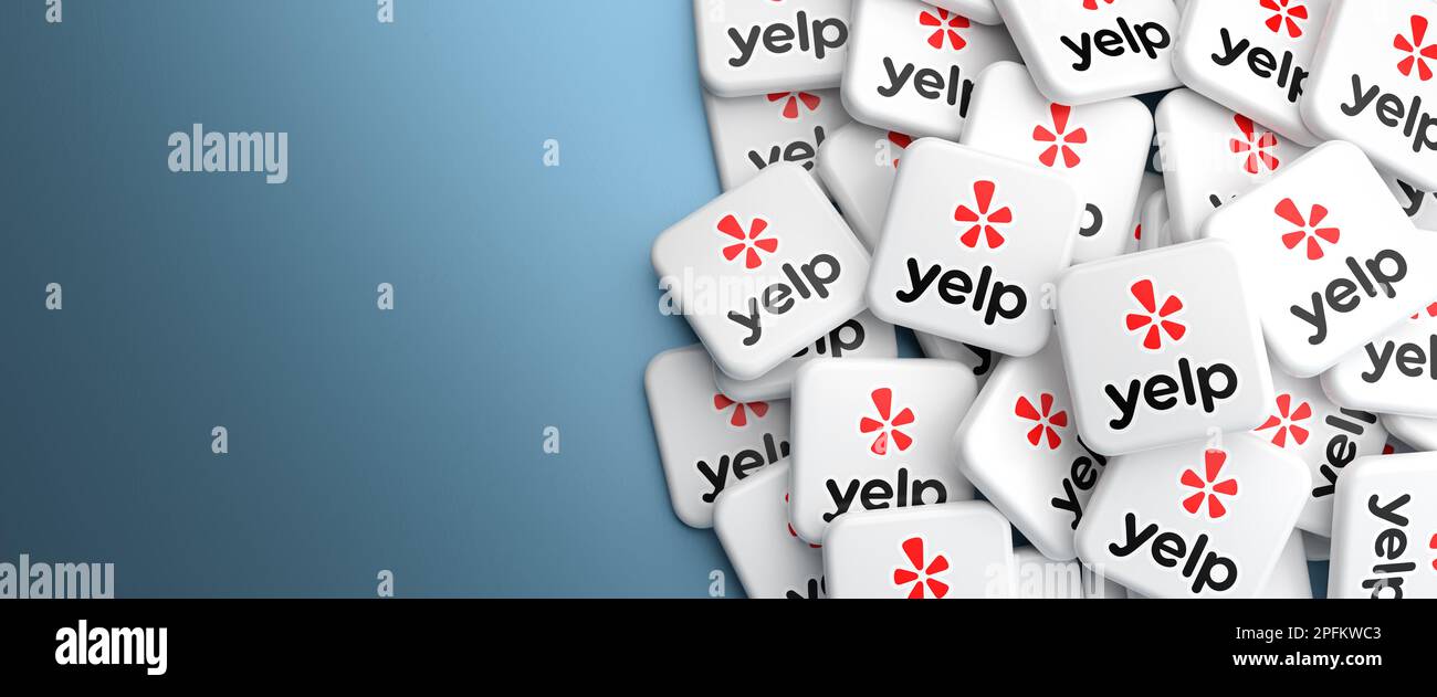 Logos of the online review platform and table reservation service Yelp on a heap on a table. Web banner format Stock Photo