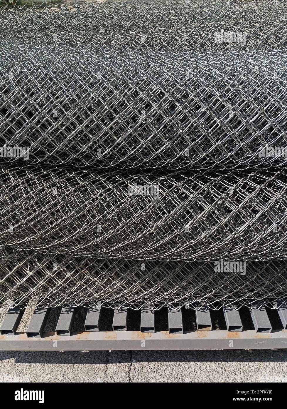 A metal mesh chainlink twisted in rolls lies on a metal base Stock Photo Alamy