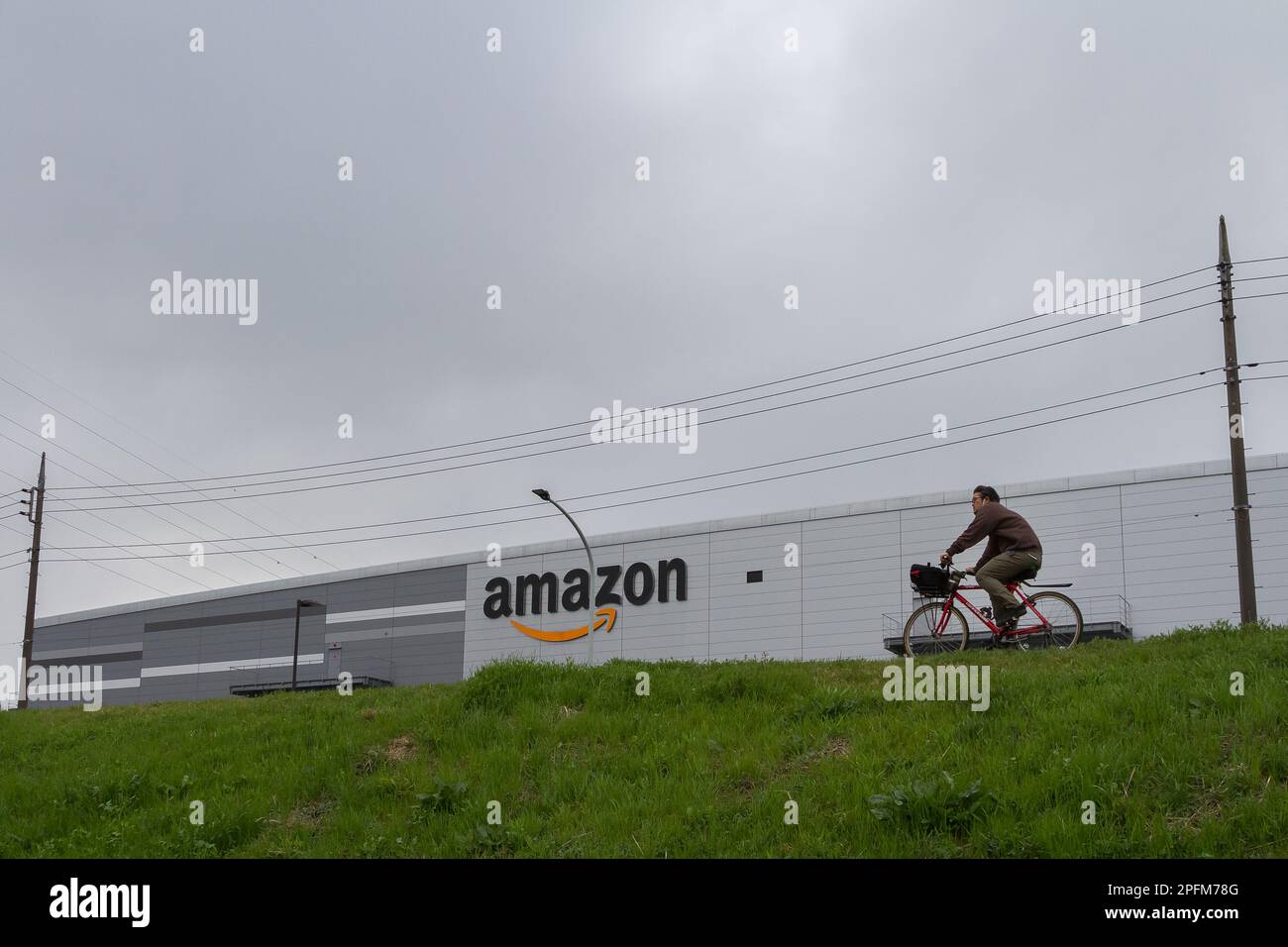 A man rides a bicycle in front of an amazon delivery center warehouse in FutakoShinchi, Tokyo