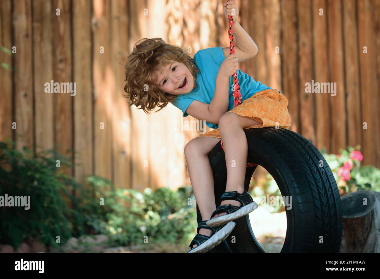 Child swing on backyard. Kid playing oudoor. Happy cute little boy