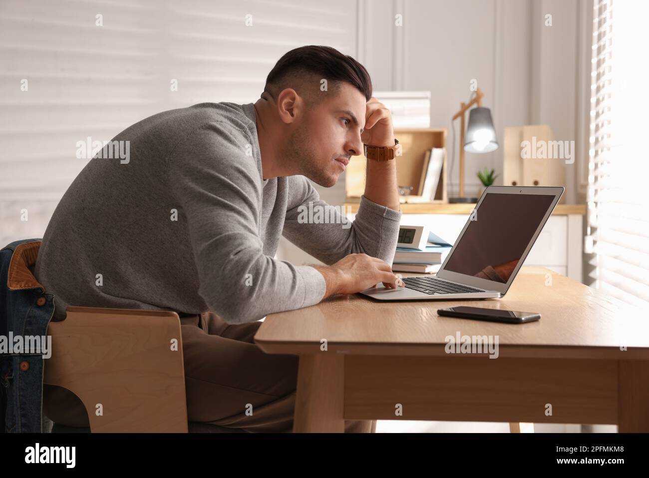 Man with poor posture using laptop at table indoors Stock Photo Alamy