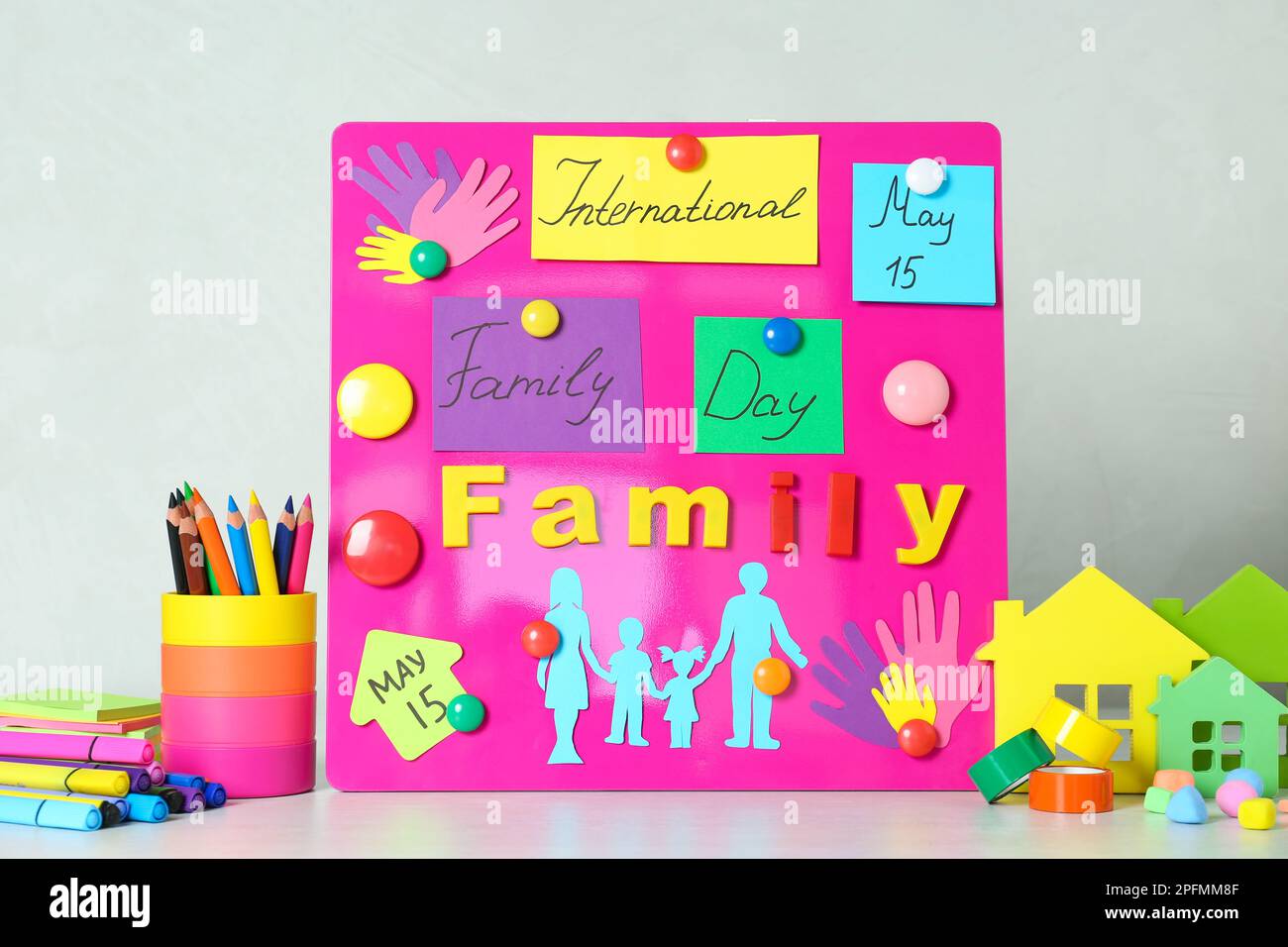 Magnetic board with text International Family Day and paper cutouts on white table Stock Photo