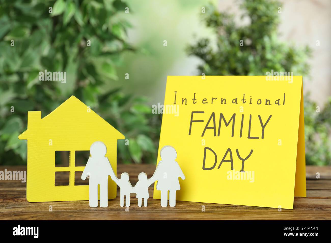 Card with text International Family Day and figures on wooden table Stock Photo
