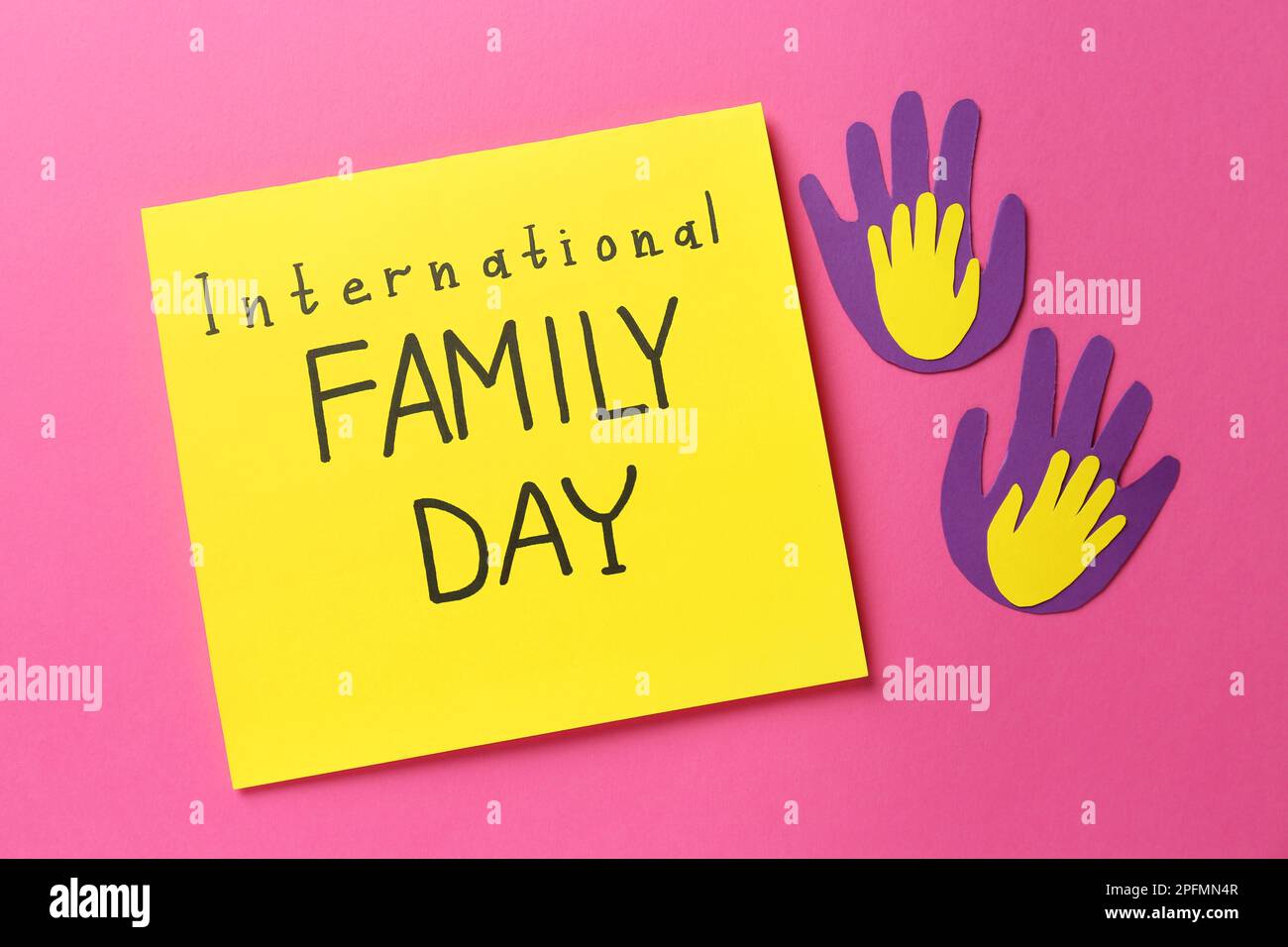 Paper palms and card with text International Family Day on pink background, flat lay Stock Photo