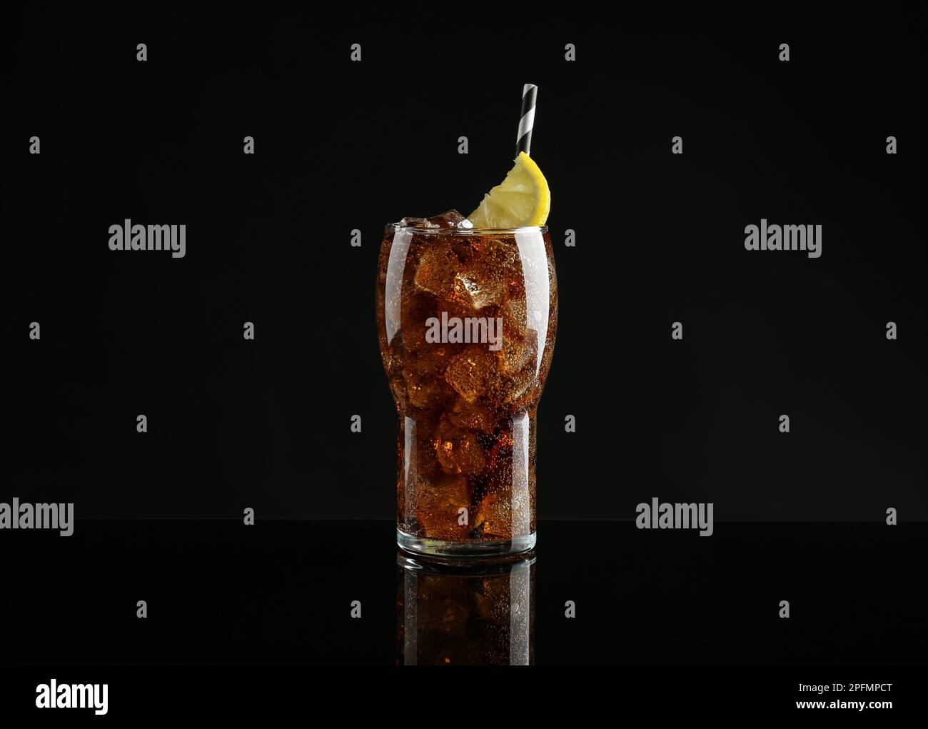Glass of refreshing soda water with ice cubes and lemon slice on black ...