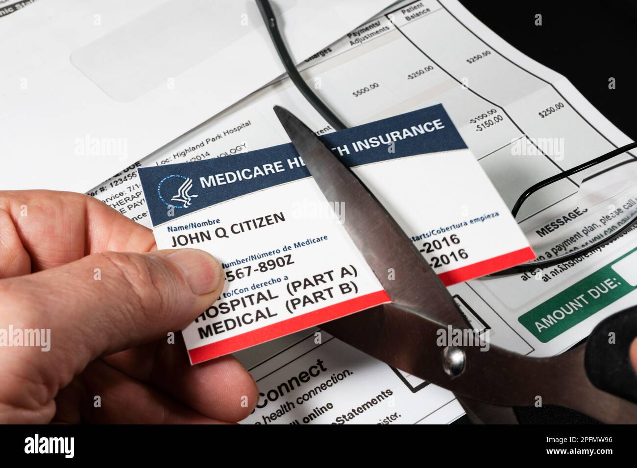 Selective focuse of man cutting fake Medicare cut with fake hospital bill in background. Stock Photo