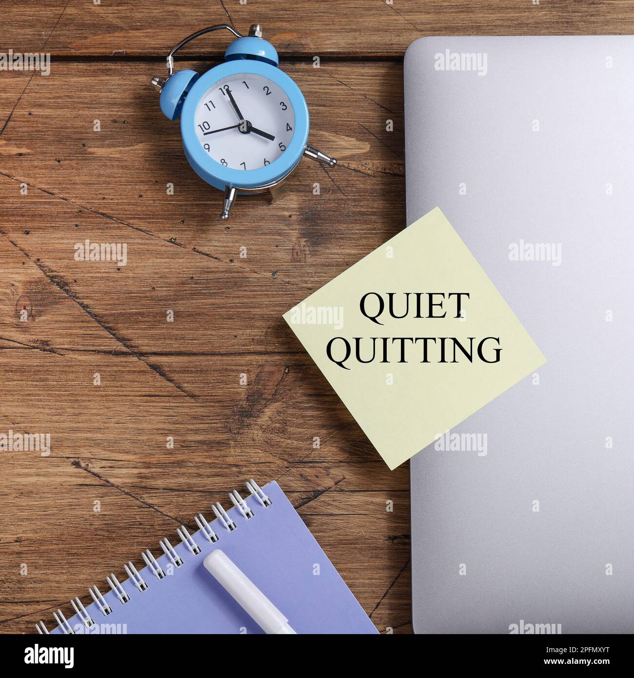quote 'Quiet quitting' on yellow sticker on computer with clock and