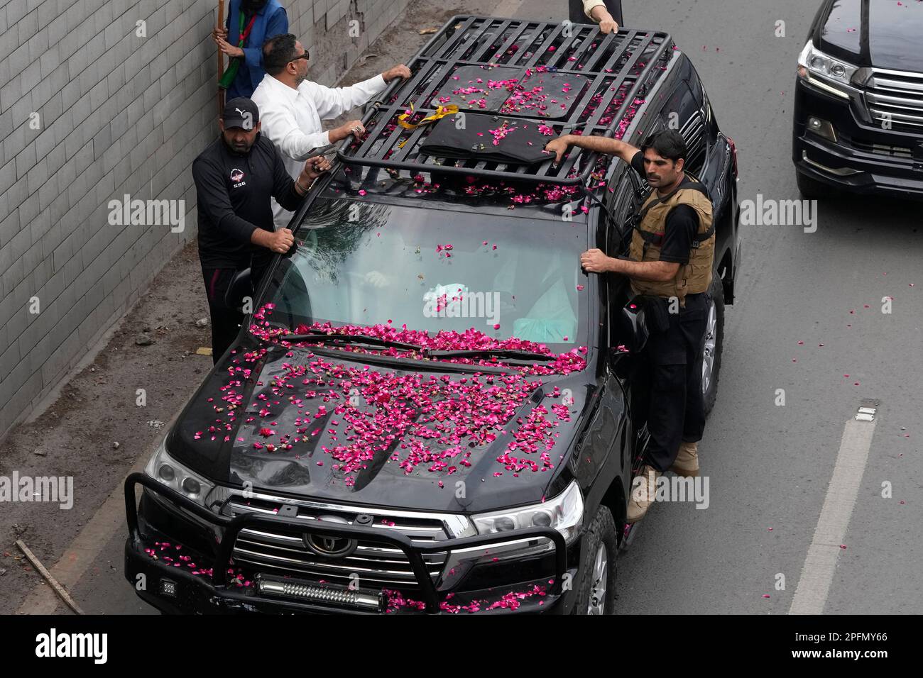 Security personnel climb on a vehicle carrying former Prime Minister