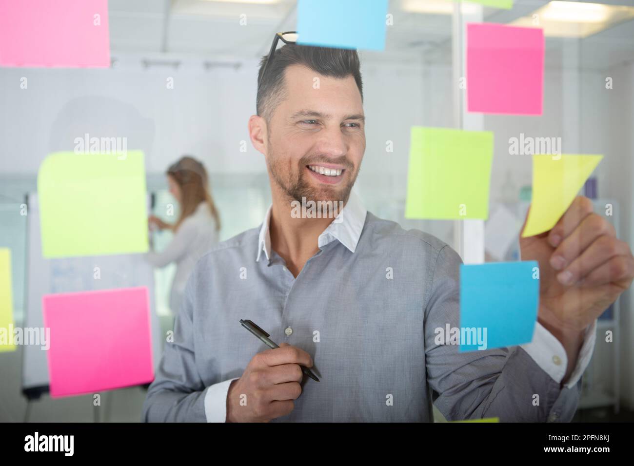 businessman removing sticky note reminder from window Stock Photo Alamy