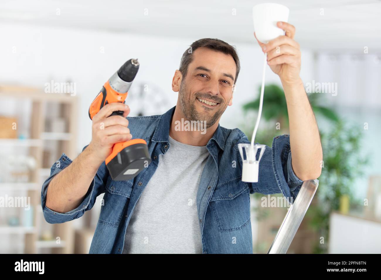 electrician fitting a ceiling light Stock Photo