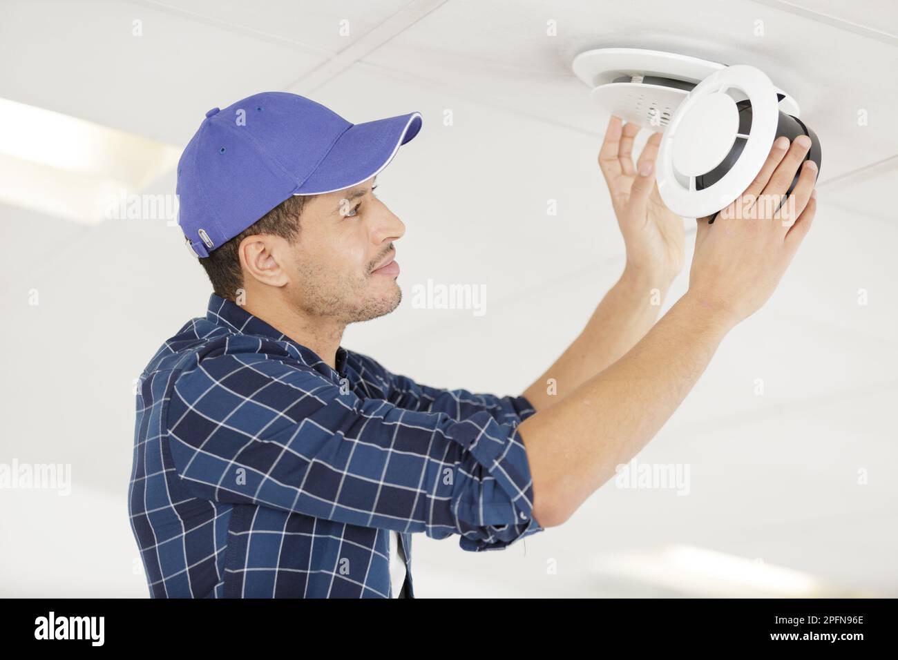 young electrician installing smoke detector on ceiling Stock Photo Alamy