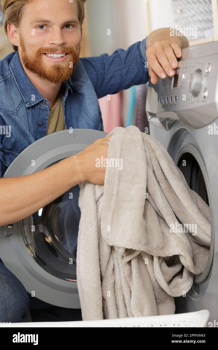 independent man putting clothes into washing machine Stock Photo