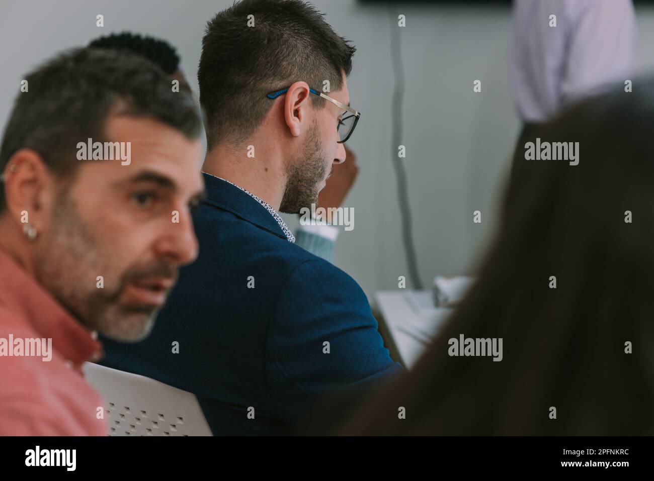Close up of business man with dark blue suit and glasess looking down while sitting at the office desk Stock Photo