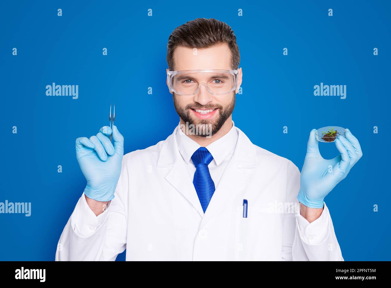 Portrait of attractive biologist in white outfit with tie, showing having forceps and vial with