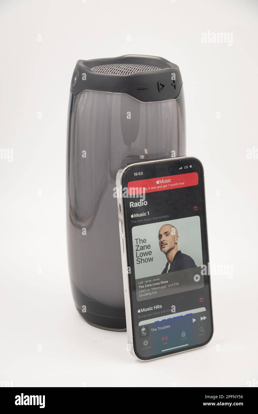 Riga, Latvia - March 15, 2023: Apple Music app on iPhone in front of  smart speaker. Stock Photo