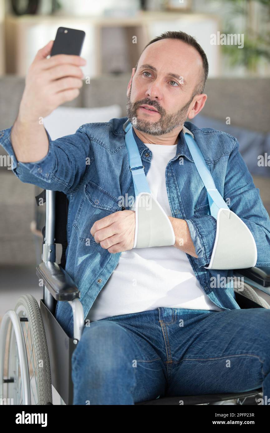 man in wheelchair with arm in sling taking selfie Stock Photo - Alamy