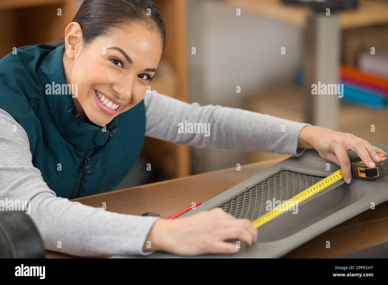 woman measuring a car part in a workshop Stock Photo