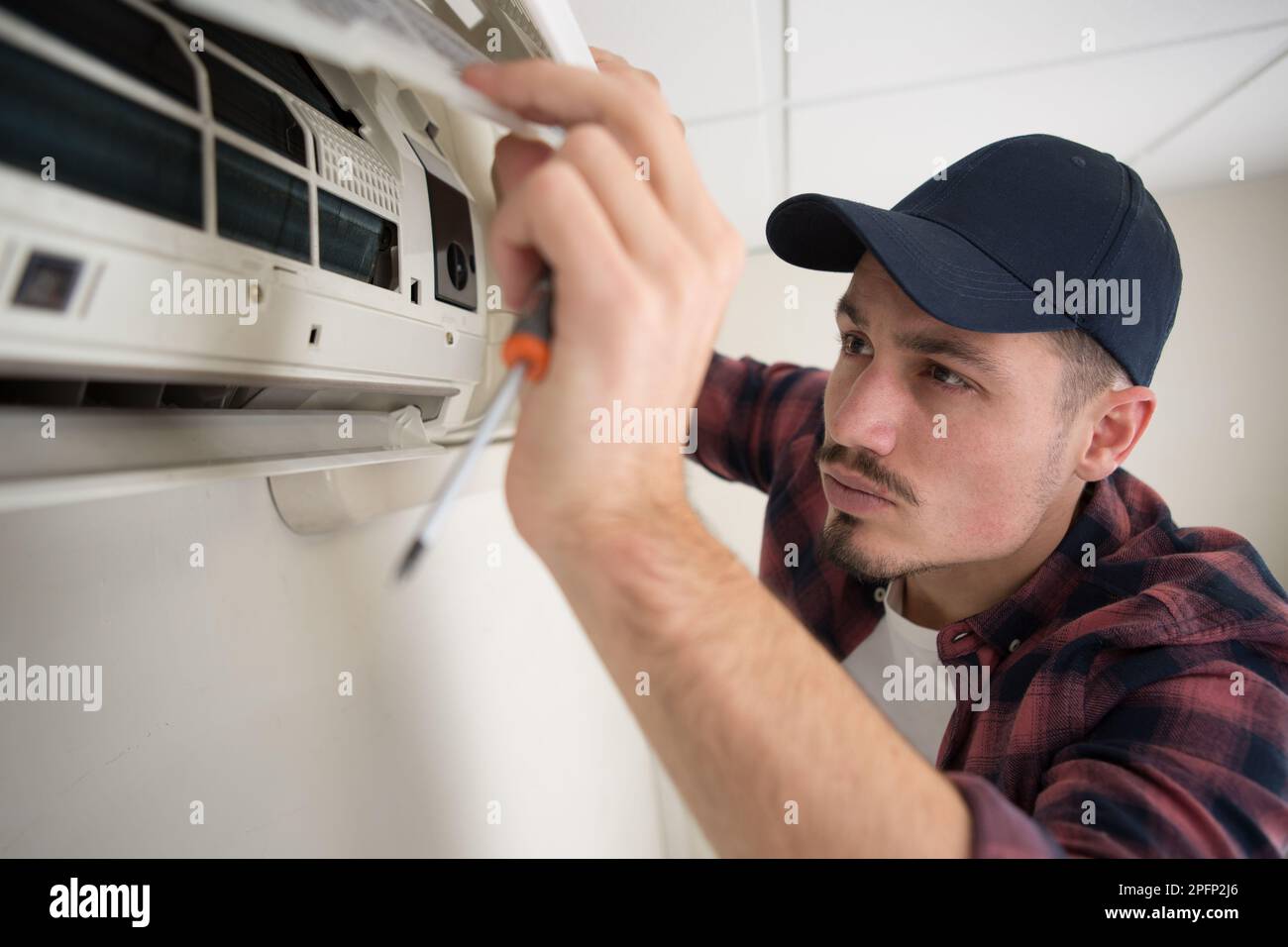 professional electrician is fixing a heavy air conditioner Stock Photo
