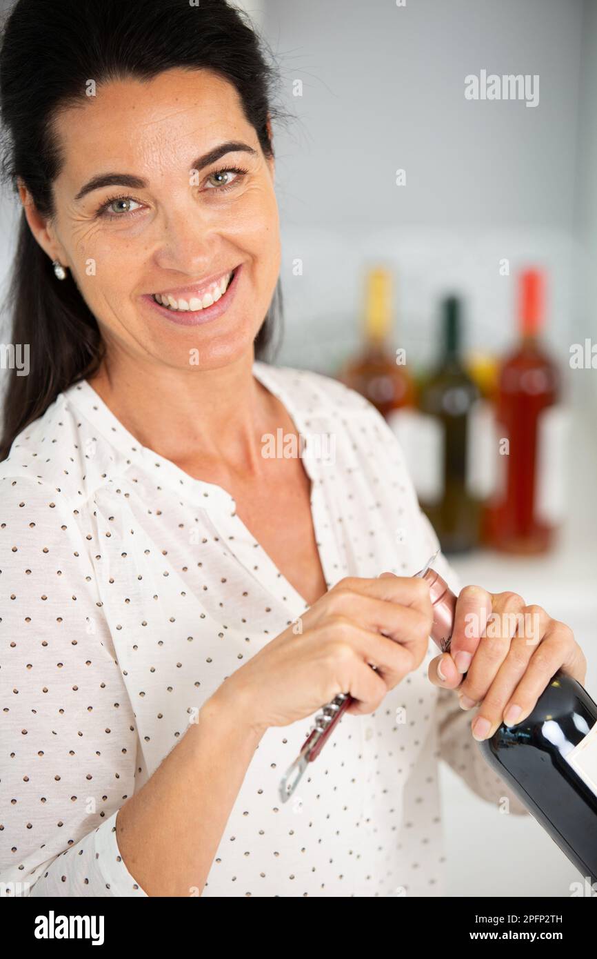 mature woman opening a bottle of wine Stock Photo - Alamy