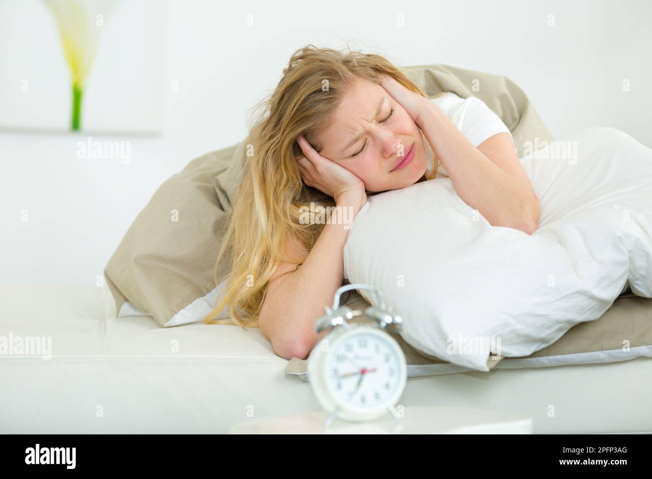 woman covering her ears alarm clock noise Stock Photo Alamy