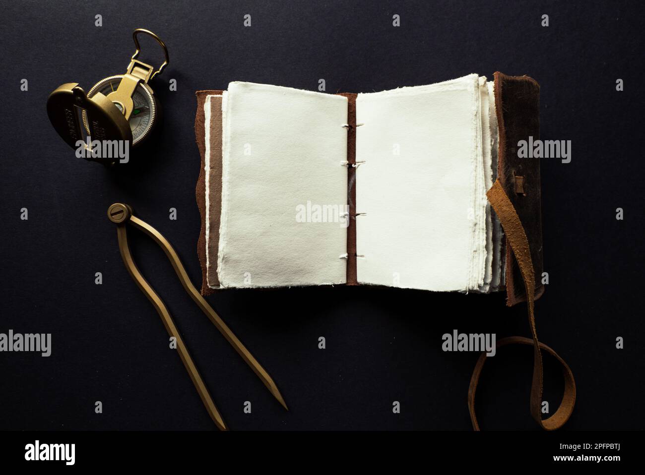 Vintage leather journal or diary on a black table with a compass next to it Stock Photo