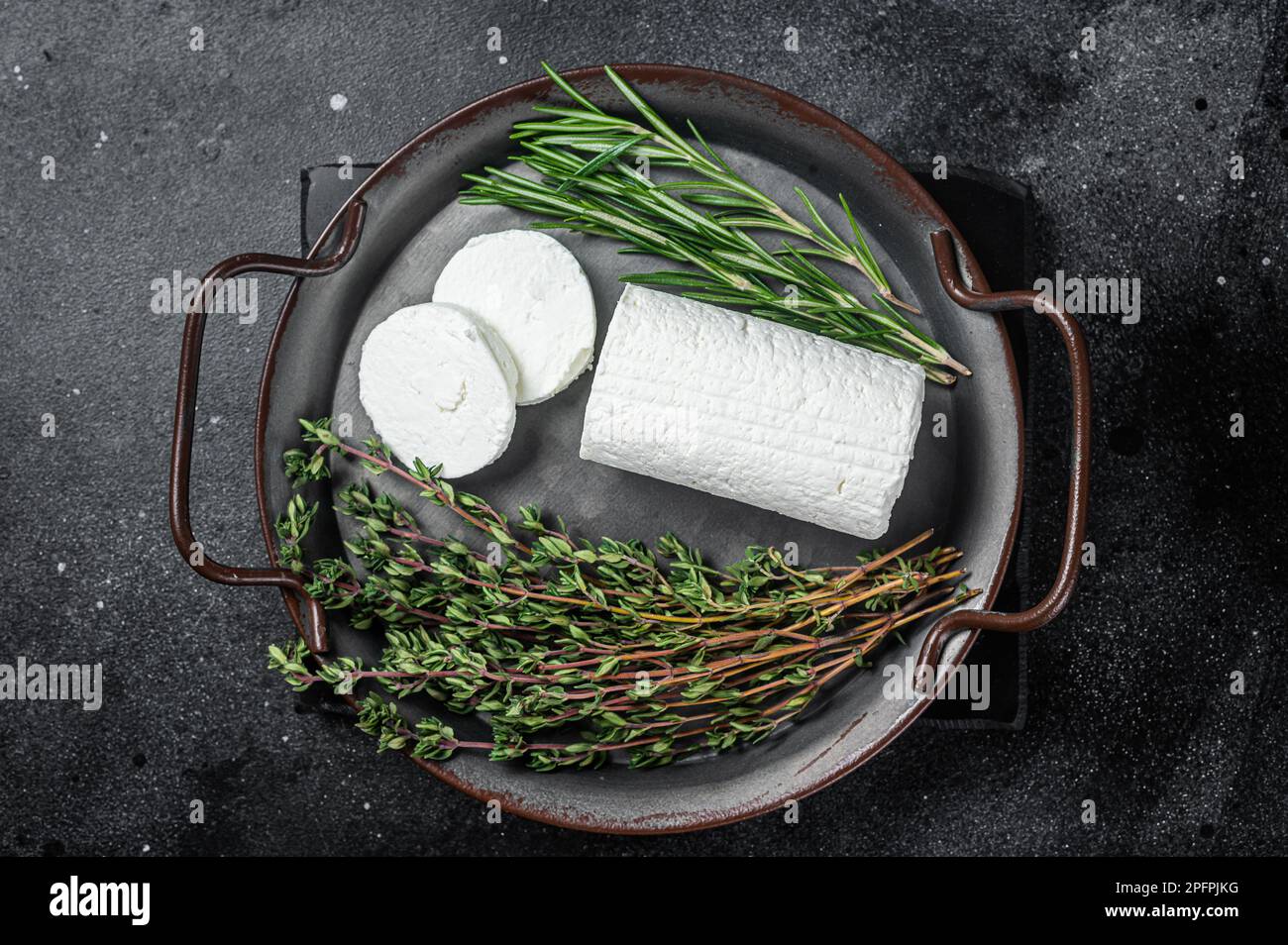 Chevre goat soft cheese with herbs on a tray. Black background. Top ...