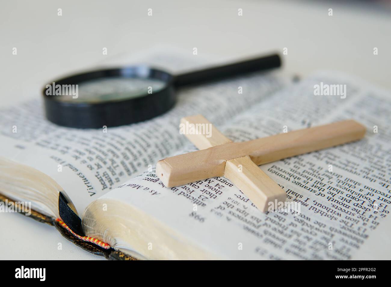 Open Holy Bible with a cross and magnifying glass. The concept of Bible