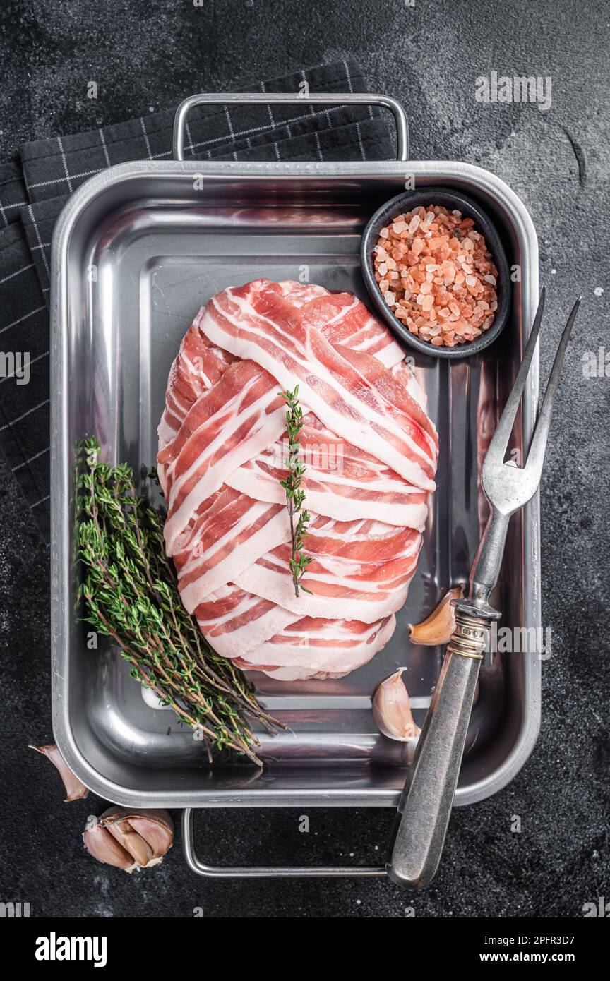 Cooking raw meatloaf with ground beef meat and bacon in steel tray