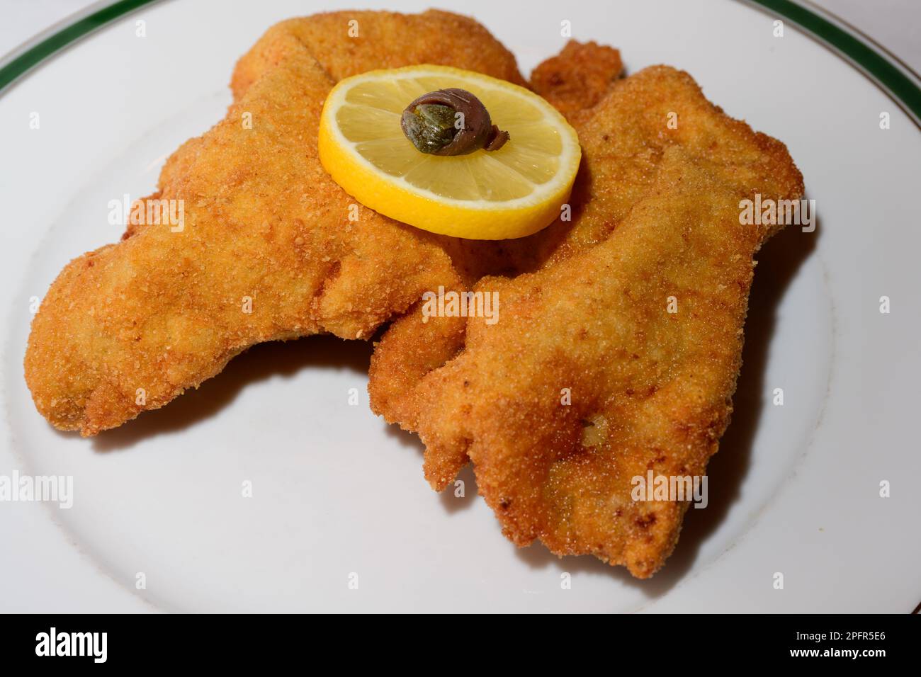 Wiener Schnitzel Breaded Fried Veal Cutlet with Viennese Garnish or Wiener Garnitur consisting of a Lemon Wheel and an Anchovy Ring Stock Photo