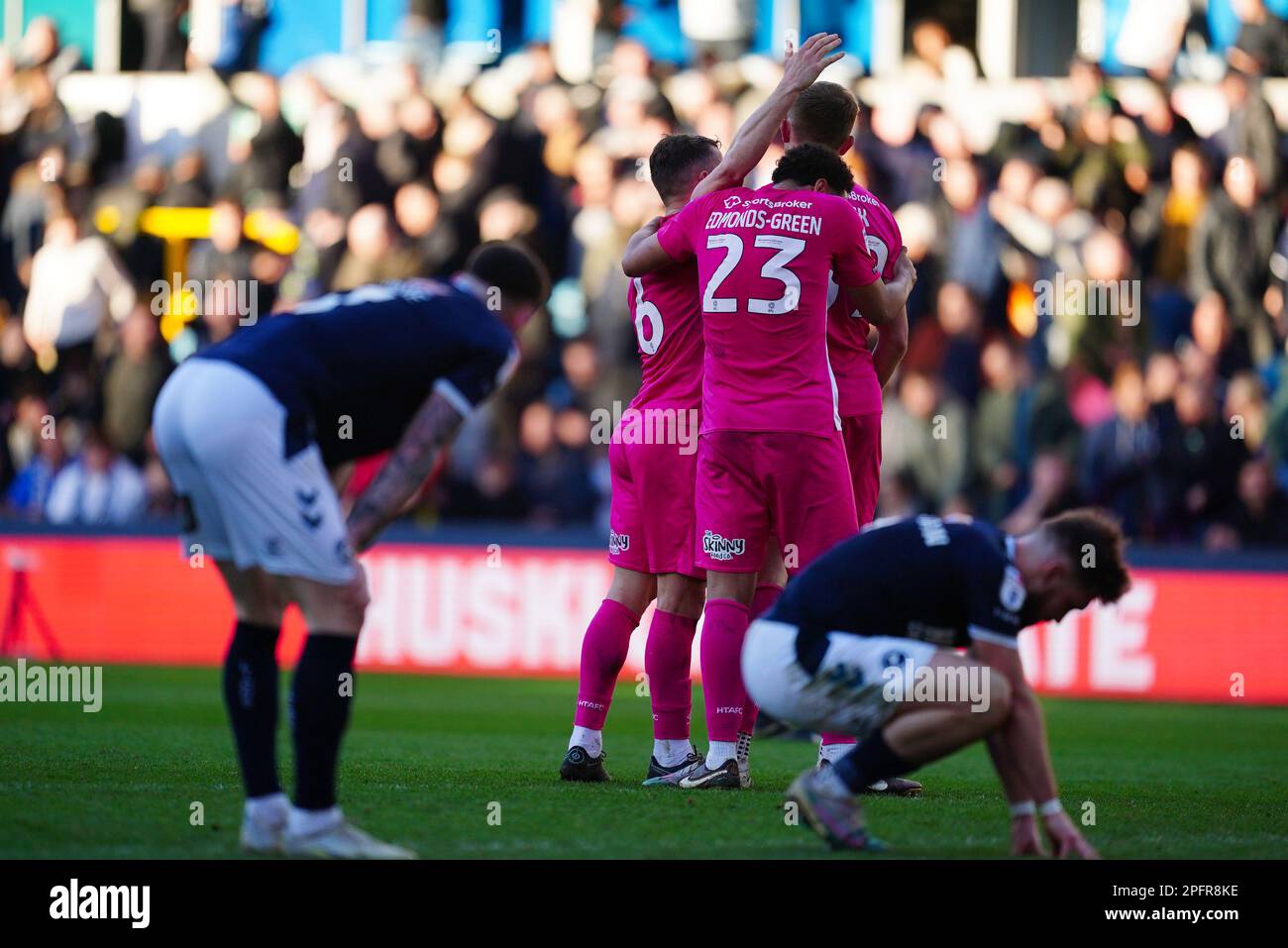 Huddersfield Town players celebrate as Millwall's players sink to their knees at the final whistle after the Sky Bet Championship match at The Den, London. Picture date: Saturday March 18, 2023. Stock Photo