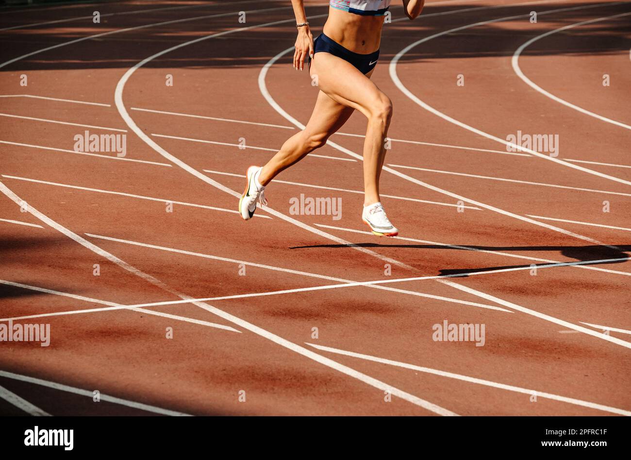 legs female athlete running race at stadium, spikes shoes for running Nike, sports photo Stock Photo