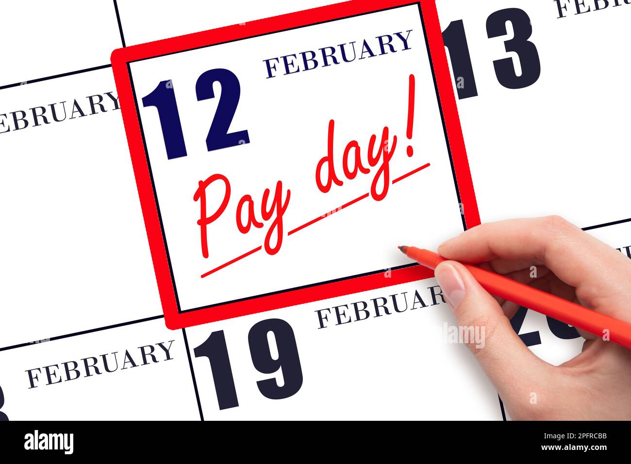 12th day of February. Hand writing text PAY DATE on calendar date February 12 and underline it. Payment due date.  Reminder concept of payment. Winter Stock Photo