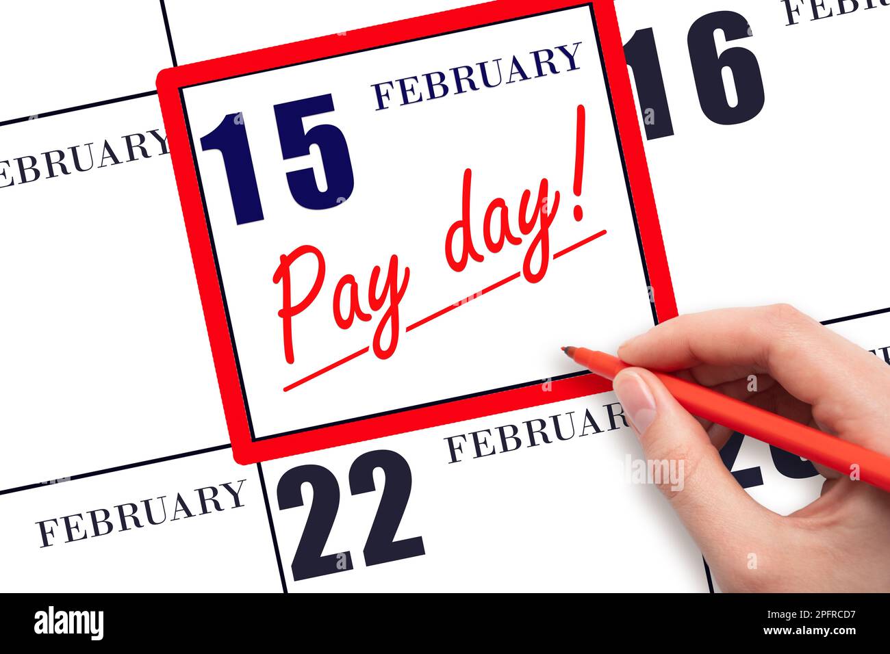 15th day of February. Hand writing text PAY DATE on calendar date February 15 and underline it. Payment due date.  Reminder concept of payment. Winter Stock Photo